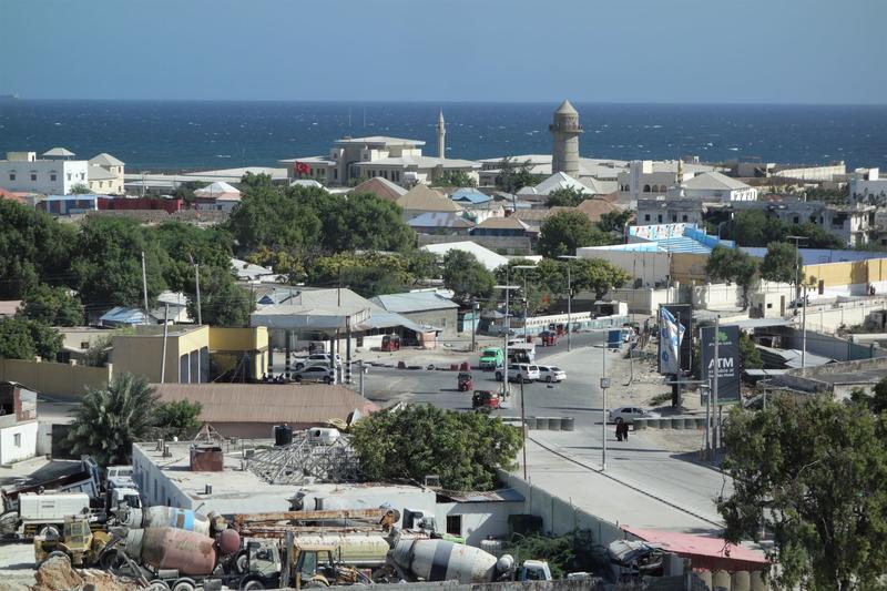An aerial shot of Mogadischu. A road runs through a town heading towards the ocean. 