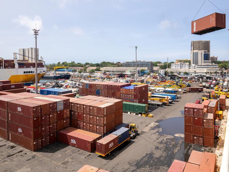 View of Dakar industrial harbour. There are rows of shipping containers and vehicles and a glimpse of a large ship in the back. Credit: manola72 - stock.adobe.com