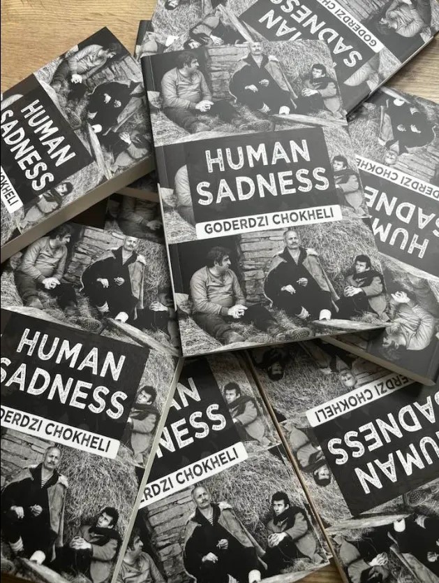 A pile of books with the title 'Human Sadness'