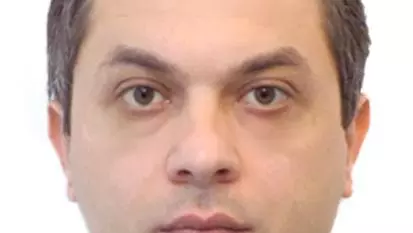 Dr Kobakhidze has short brown hair. He is wearing a shirt and blue jumper