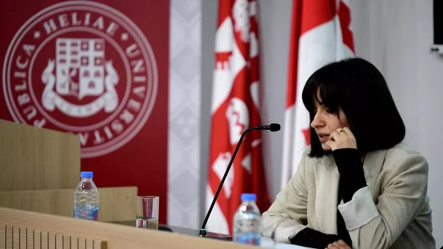 Dr Berikashvili has short black hair and is wearing a light grey blazer. She is leaning on a lectern, speaking into a microphone