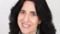Graciela has long dark hair and she is smiling at the camera. 