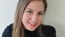 Belen has long dark blonde hair and is smiling at the camera. She is wearing a black jumper