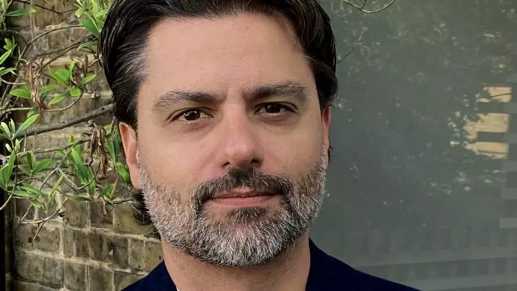 felipe krause has short dark hair and a grey beard. He's wearing a white t shirt under a black jacket