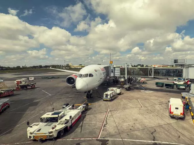 Commercial Airplane with Luggage and Service Vehicles at Jomo Kenyatta International Airport in Nairobi 
