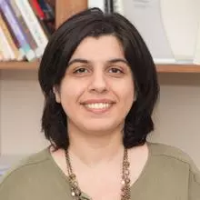 Dr Lobzhanidze has dark-shoulder length hair and is wearing a light green top with a beaded necklace