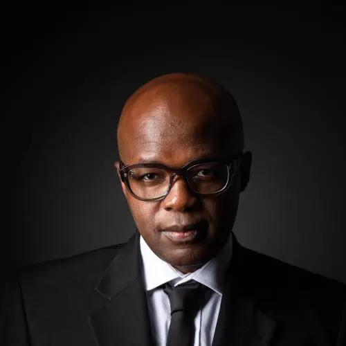 Profile photo of Miles Tendi wearing dark rimmed glasses, a white shirt, black suit and black tie 
