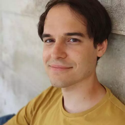 Marco has short brown hair and is wearing a yellow t shirt