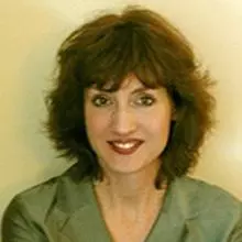 Patricia has shoulder length dark brown hair with a fringe. She's smiling at the camera. She's wearing a lime green coloured jacket
