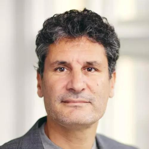 diego has dark grey thick curly hair and brown eyes. He's wearing a light grey top under a smart dark grey jacket. 