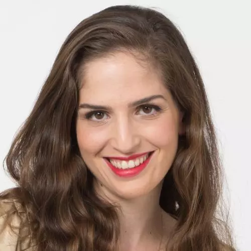 Dr Alfi-Nissan has long brown hair and brown eyes. She is smiling broadly at the camera.