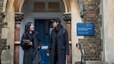 Two people chatting and walking down the steps outside OSGA Bevington Road building