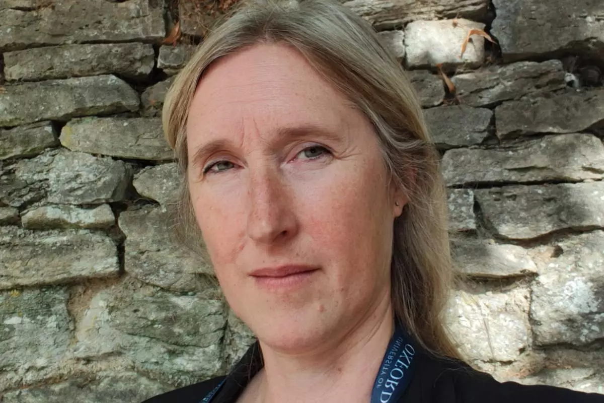 Dr Eklund has long blond hair and is wearing a dark blazer, standing in front of an old brick wall