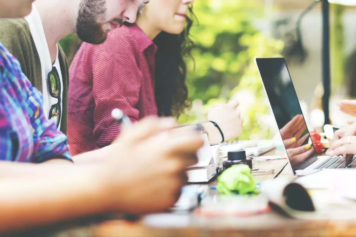 A group of students around a table with laptops and books