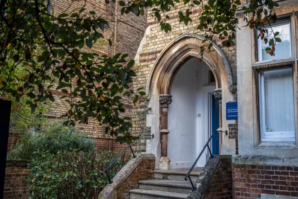 The front entrance to OSGA buildings, with an arched porchway surrounded by trees.